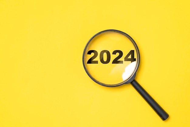 2024 anos dentro do vidro da lupa em fundo amarelo para foco e preparação mudança de ano novo e início de um novo conceito de estratégia de alvo de negócios