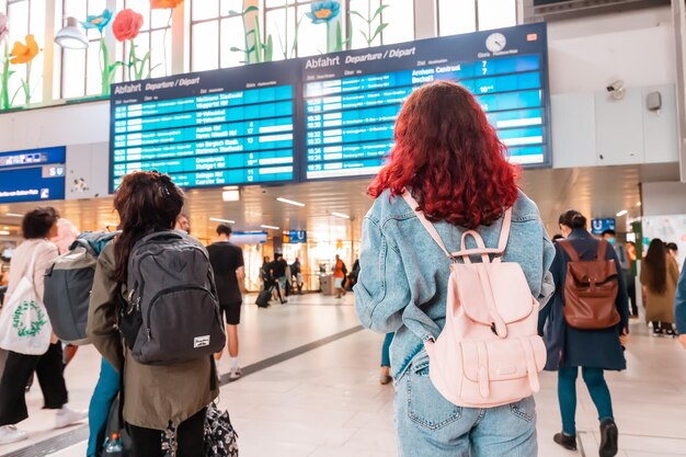 21 de julho de 2022 Dusseldorf, Alemanha Garota com mochila olhando o horário de informações e esperando o trem atrasado na plataforma