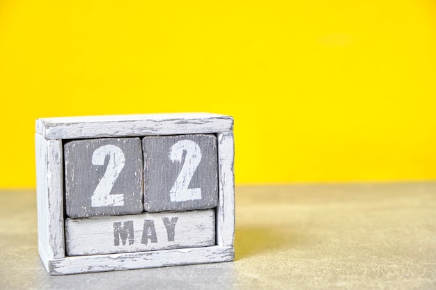 22. Mai Kalender aus Holzwürfeln gelber Hintergrund mit einem leeren Platz für Ihren Text