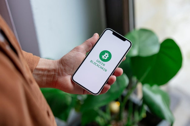 23 de novembro de 2021 - wroclaw, polônia: homem segura iphone com logotipo verde eco bitcoin e texto blockchain. tendência de 2022 anos