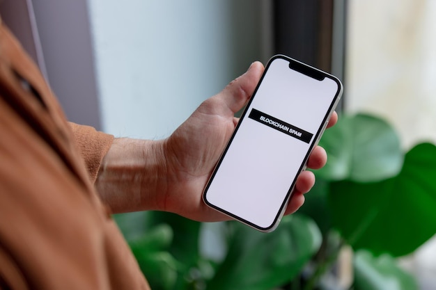 23 de noviembre de 2021 - Wroclaw, Polonia: un hombre sostiene un iPhone con texto de spam de blockchain. Tendencia del año 2022