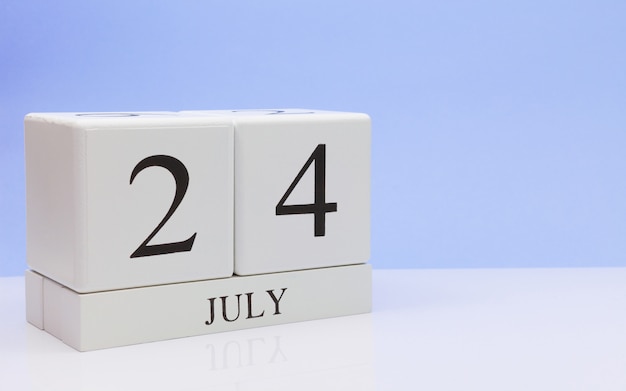 24 de julio. Día 24 del mes, calendario diario en mesa blanca con reflejo, con fondo azul claro.