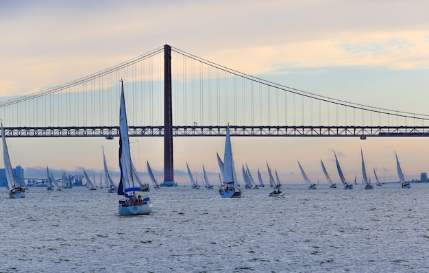 25. April-Brücke über Boote, die auf dem Meer gegen den Himmel segeln