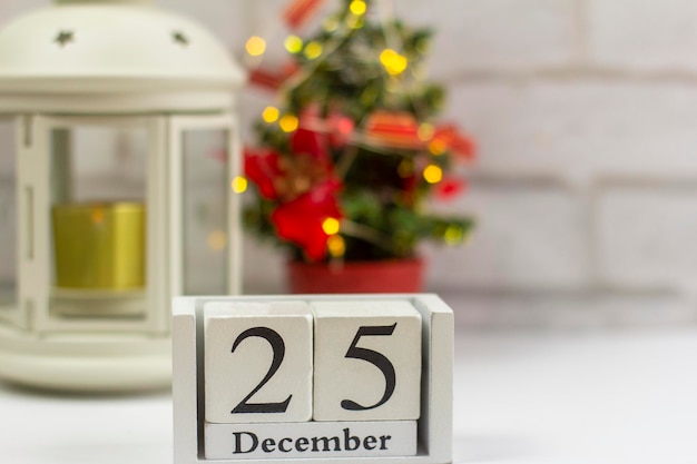 25 de dezembro em um calendário de madeira branco sobre um fundo claro ao lado da árvore de Natal. O conceito de Natal.