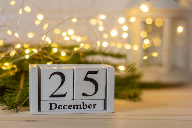 25 de dezembro em um calendário de madeira branco sobre um fundo de madeira ao lado da árvore de Natal. O conceito de Natal.