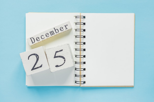 25. Dezember auf einem hölzernen Kalender auf einem Lehrbuch. Weihnachten und Neujahrskonzept