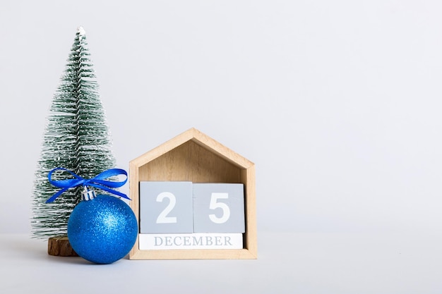 25. dezember Weihnachtskomposition auf farbigem Hintergrund mit einem Holzkalender mit einer Geschenkbox Spielzeugkugel Kopierraum