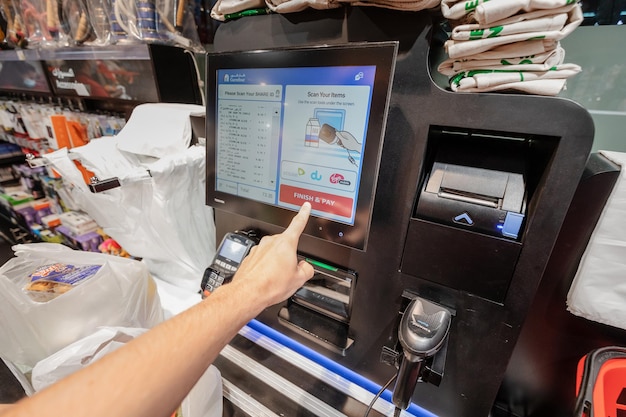 25 de febrero de 2021 Emiratos Árabes Unidos Dubai hombre cliente paga por una compra en un supermercado utilizando una terminal de caja de autoservicio