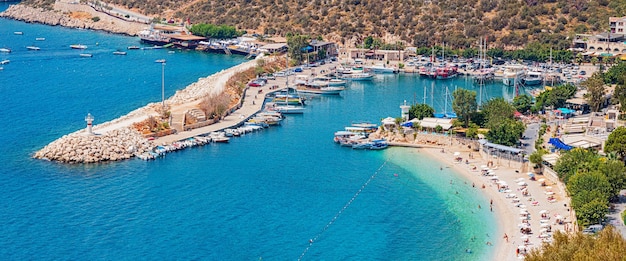 27. August 2021 Kalkan Türkei Badeort Kalkan in der Türkei Leuchtturm am Eingang zur Marina und Strand mit weißem Sand mit Urlaubern