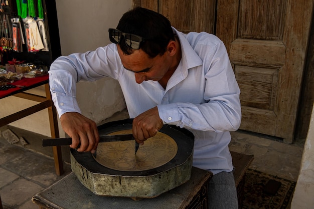 27 de junho de 2023 BUKHARA UZBEKISTÃO O mestre fazendo o trabalho de metal para vendê-lo como uma lembrança