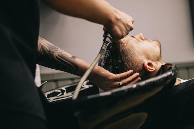 27022020 Odessa Ucrânia O processo de lavar o cabelo na cabeça do cliente em uma barbearia masculina usando xampu