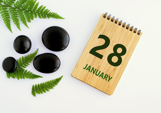 Foto 28 de janeiro 28º dia do mês data do calendário bloco de notas pedras pretas folhas verdes mês de inverno o conceito do dia do ano