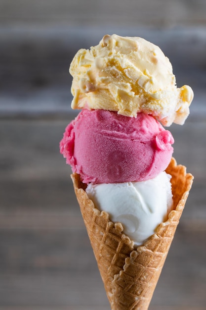 Foto 3 bolas de sorvete italiano na mão gelato de sorvete de frutas na torre de sorvete de cone