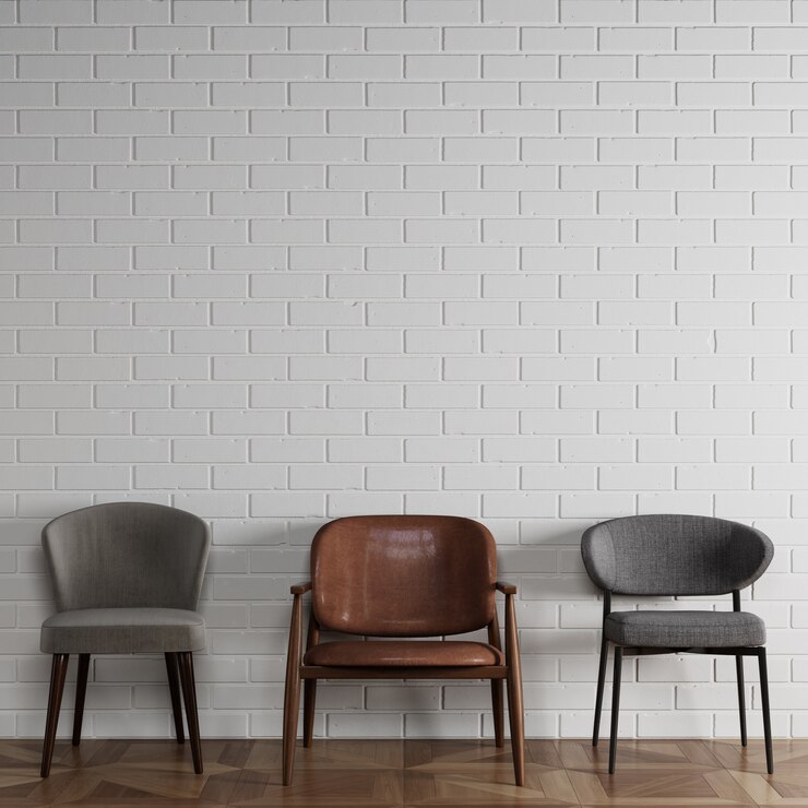 3 cadeiras diferentes em estilo moderno, em frente a parede de tijolos brancos com copyspace