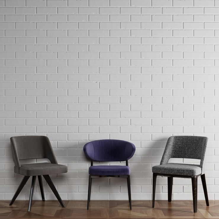 3 cadeiras diferentes em estilo moderno, em frente a parede de tijolos brancos com copyspace