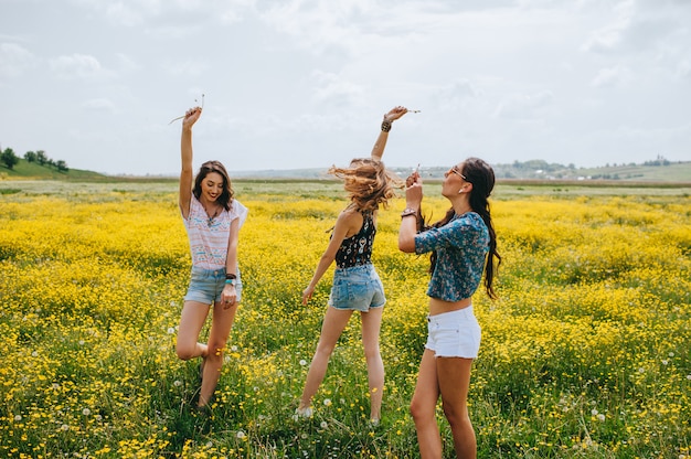 3 garota bonita hippie em um campo de flores amarelas