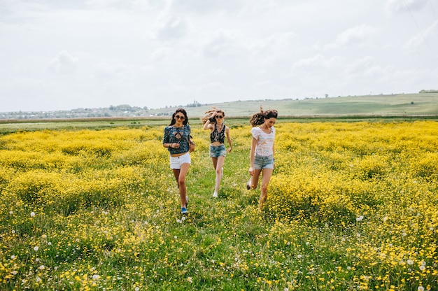 3 garota bonita hippie em um campo de flores amarelas