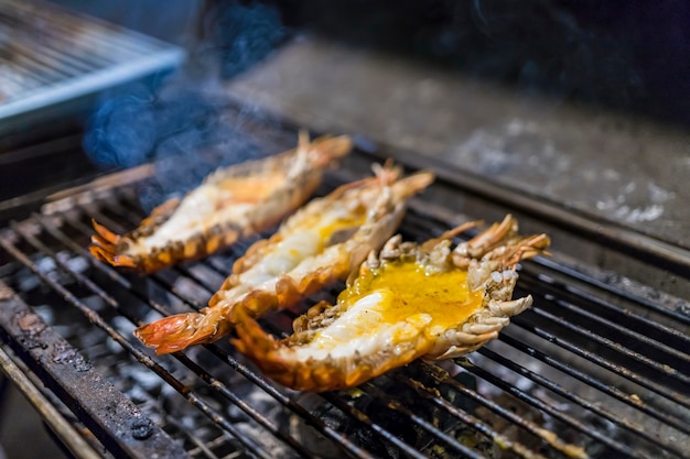 3 große Garnelen grillen auf dem Grill. Rauch steigt in der Nacht. Lieblings thailändisches Essen.