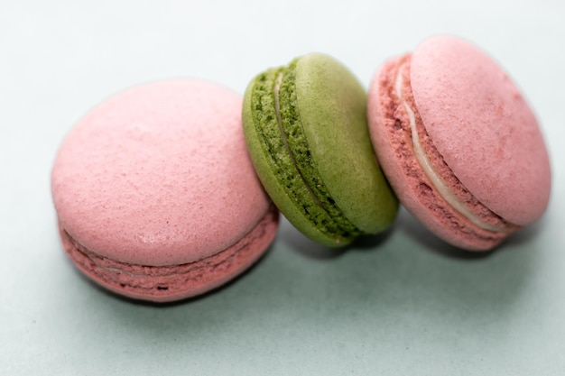 3 macarons deliciosos com ou sem saco plástico sobre fundo verde 2 macaroon rosa e um verde