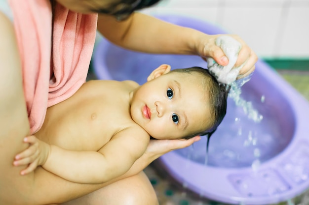 3 Monate nettes Baby, das mit ihrer Mutter im Badezimmer badet.