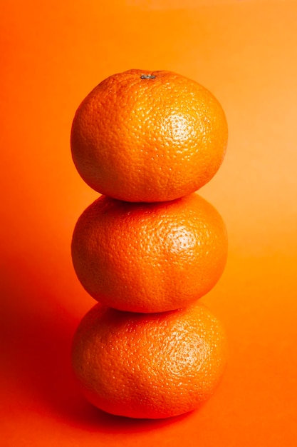 3 naranjas colocadas una encima de la otra en un plano cerrado y un fondo del mismo color naranja Concept real food