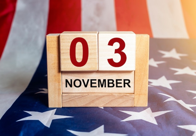 3 de noviembre, día de las elecciones en Estados Unidos. Fecha en calendario de madera con bandera americana en el fondo.