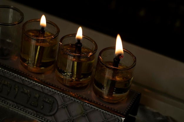 3 velas acesas na menorá em um fundo escuro