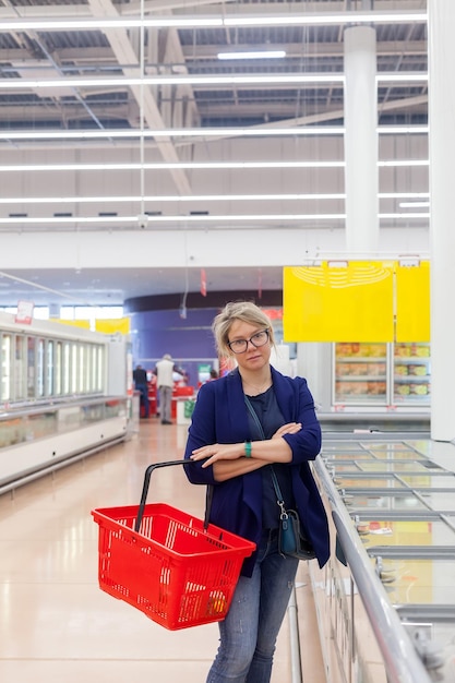 30-jähriges Mädchen, das Tiefkühlkost im Supermarkt auswählt