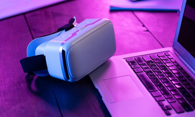 3D-360-VR-Headset-Brille auf Laptop-Tastatur-Arbeitstisch in violettem Neonlicht