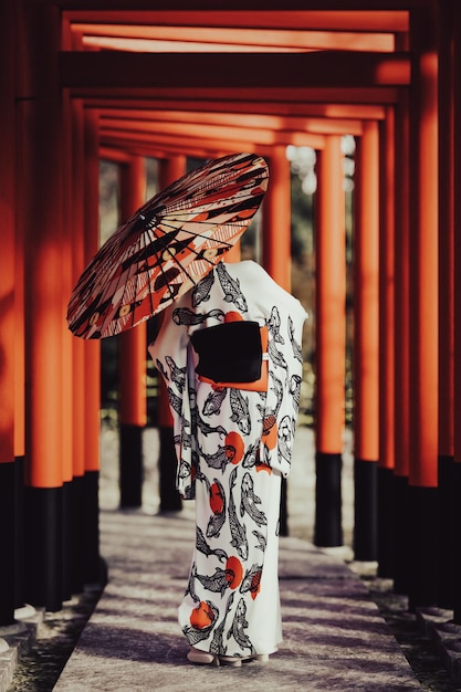 3d-Darstellung Eine Frau in einem Kimono, die mit einem Regenschirm im Torii-Gate-Tunnel spazieren geht