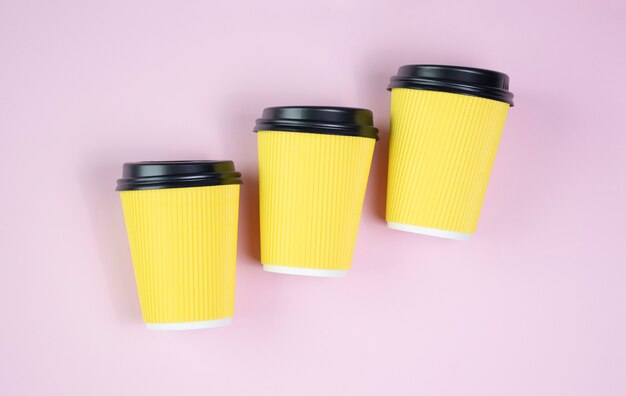 3D render de tazas de café de papel para llevar sobre fondo rosa, coloridos vasos desechables