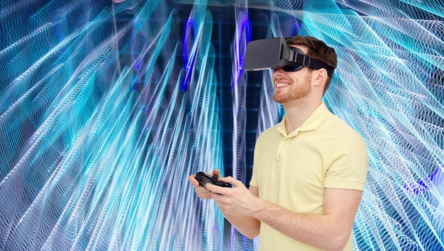 3D-Technologie, Virtual Reality, Entertainment und People-Konzept - glücklicher junger Mann mit Virtual-Reality-Headset oder 3D-Brille, der mit Gamecontroller-Gamepad über spiralförmigem Neonlichthintergrund spielt