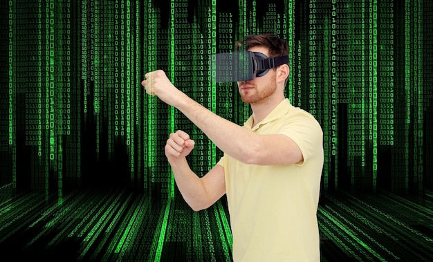 3D-Technologie, Virtual Reality, Entertainment und People-Konzept - junger Mann mit Virtual-Reality-Headset oder 3D-Brille, der ein Spiel spielt und über Binärcode-Hintergrund kämpft