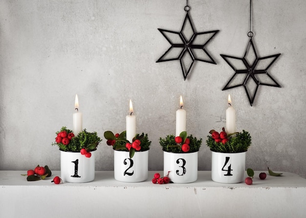 4. Advent. Weihnachtsschmuck mit weißen Adventskerzen in vier Emailtöpfen mit Zahlen