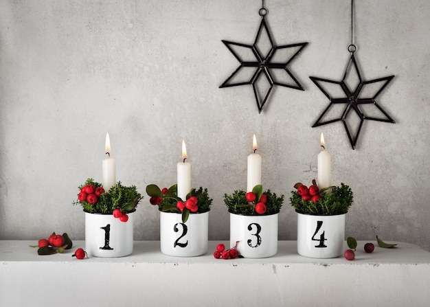 4. Advento. Decorações de natal com velas brancas do advento em quatro potes de e-mail com números