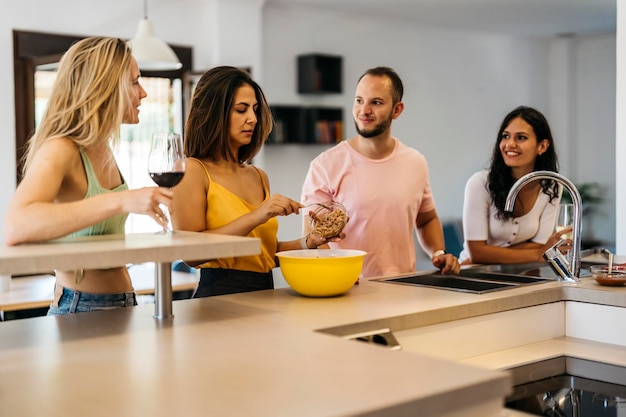 4 amigos conversando em um balcão de cozinha enquanto preparam comida