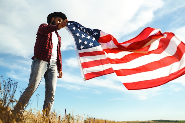 4 de Julho Bandeira Americana Viajante com a bandeira da América O homem com um chapéu uma camisa de mochila