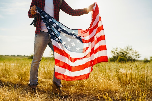 4 de Julho Bandeira Americana Viajante com a bandeira da América O homem com um chapéu uma camisa de mochila