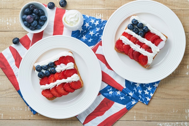 4 de julho Comida do Dia da Independência Americana Sanduíche de bandeira americana com morangos mirtilos chantilly creme de queijo macio na torrada de pão Ideia de café da manhã do Dia da Independência ou Patriótica Mock up