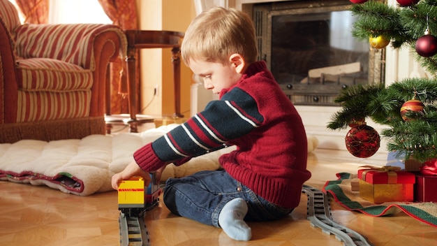 4 imágenes de k de niño pequeño construyendo tren de juguete y ferrocarril de ladrillos y bloques debajo del árbol de Navidad. Niño recibiendo regalos y regalos de Santa Claus en celebraciones y vacaciones de invierno