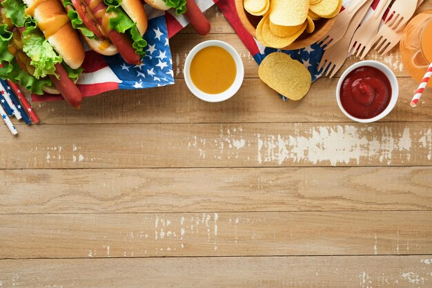 4. Juli, amerikanischer Unabhängigkeitstag, traditionelles Picknick-Essen, Hot Dog mit Kartoffelchips und Cocktail, amerikanische Flaggen und Symbole der USA, patriotischer Picknick-Feiertag auf hölzernem Hintergrund, Draufsicht