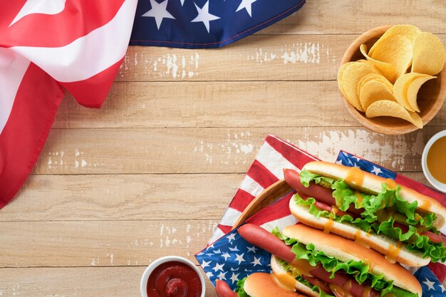 4 de julio Día de la Independencia de Estados Unidos comida de picnic tradicional Perro caliente con papas fritas y cóctel Banderas y símbolos estadounidenses de vacaciones de picnic patriótico de EE. UU. Sobre fondo de madera Vista superior