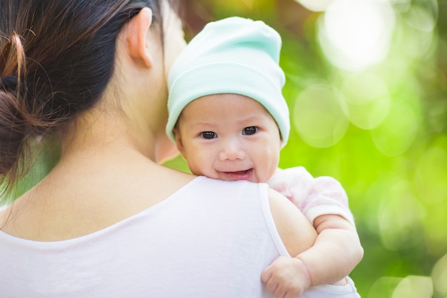 4 meses bebé sintiéndose feliz y sonríe con su madre en el jardín