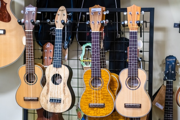 4 pequeñas guitarras acústicas tradicionales havaiian ukelele colgando en la tienda de música