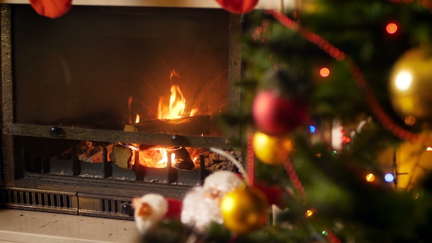 4k imagens de fogo queimando na lareira ao lado da árvore de natal decorada com luzes coloridas brilhantes. foto perfeita para celebrações e feriados de inverno