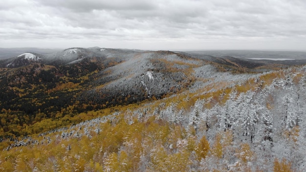 Foto 4k-luftbild der berge, die vom ersten schnee bedeckt sind schnee auf berggipfeln und wunderschöner grüner kiefernwald die wintersaison steht vor der tür