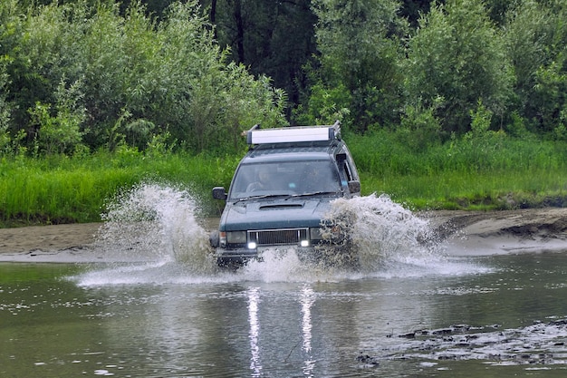 4x4-Offroad-Auto überquert eine Wasserbarriere mit Spritzern bei hoher Geschwindigkeit