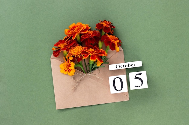 5 de octubre Ramo de flor de naranja en sobre artesanal y fecha de calendario sobre fondo verde Concepto mínimo Hola plantilla de otoño para su tarjeta de felicitación de diseño