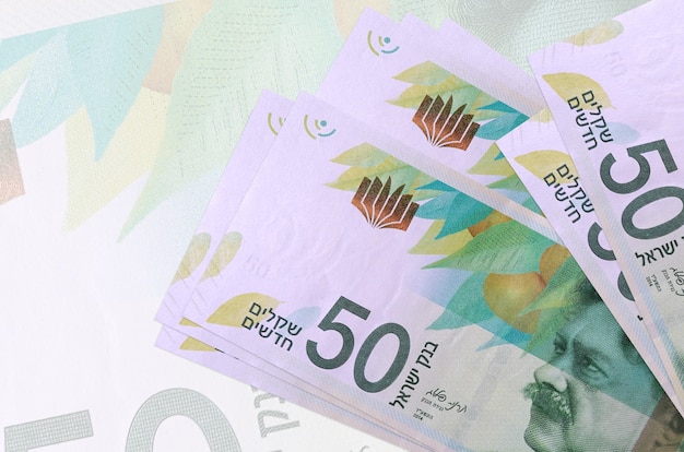 50 billetes nuevos shekels israelíes se encuentran en la pila sobre el fondo de un gran billete semitransparente