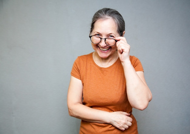 55-jährige Frau mit Brille lacht und schaut in die Kamera